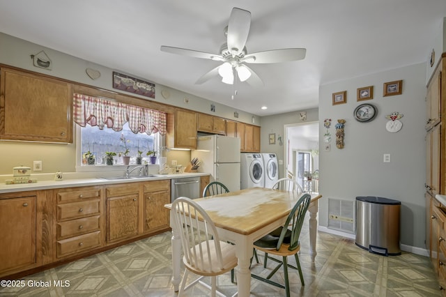 kitchen with light countertops, freestanding refrigerator, brown cabinets, light floors, and washer and clothes dryer