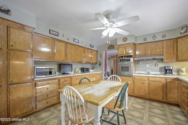 kitchen featuring light floors, under cabinet range hood, stainless steel appliances, and light countertops