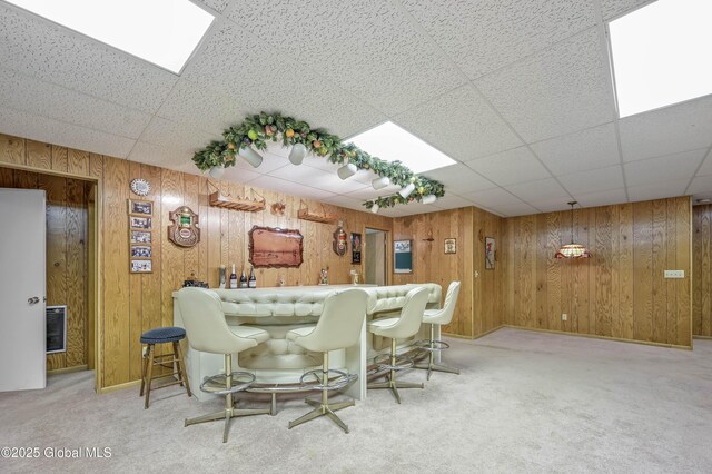 bar with carpet floors, a paneled ceiling, wood walls, and a dry bar