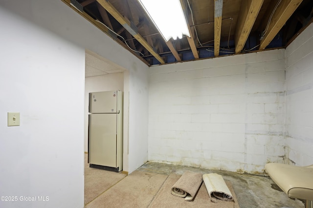 unfinished below grade area with freestanding refrigerator and concrete block wall