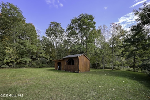 view of yard featuring a forest view, a shed, and an outdoor structure