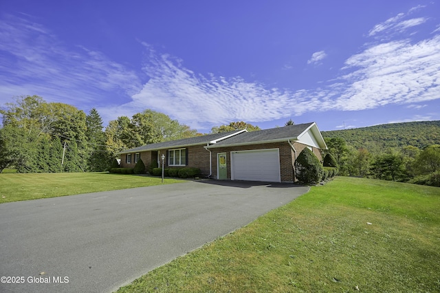 ranch-style house featuring driveway, a garage, a front yard, and brick siding