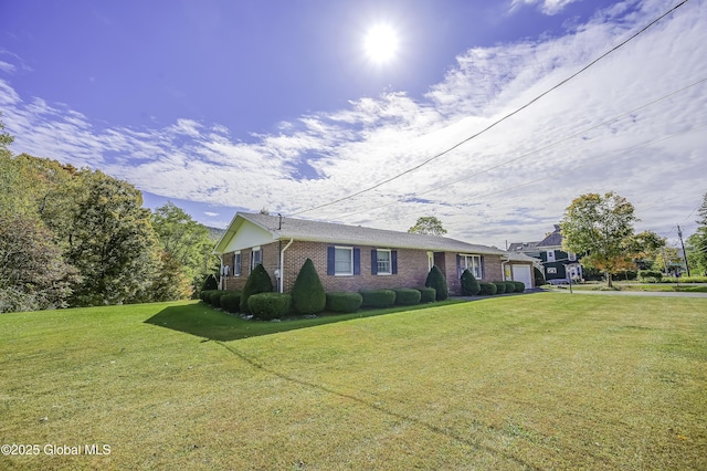 view of front facade with an attached garage, driveway, a front yard, and brick siding