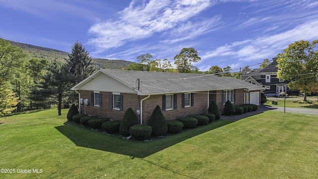 view of property exterior featuring a garage, brick siding, driveway, a lawn, and roof with shingles