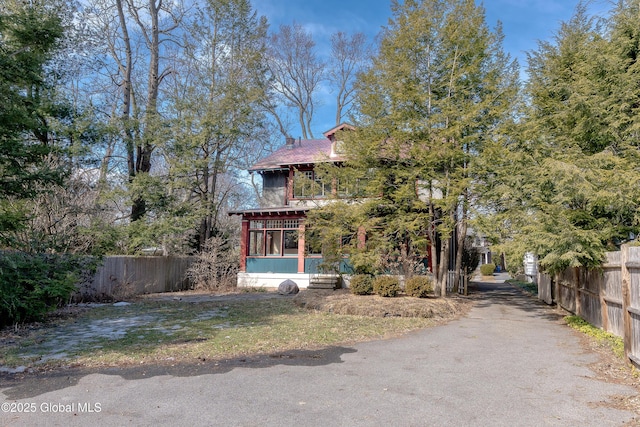 view of front of house featuring fence, driveway, and a sunroom