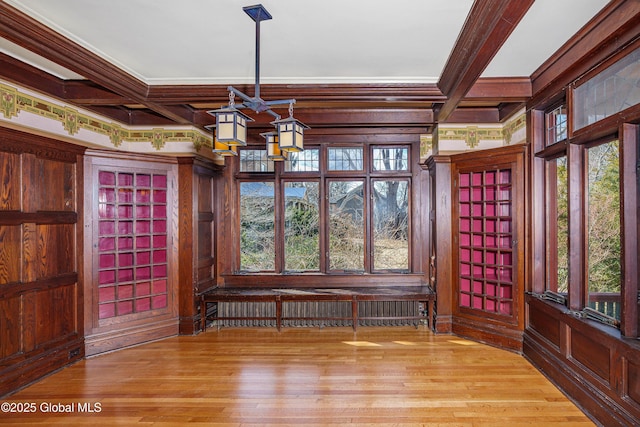 unfurnished dining area featuring beamed ceiling, coffered ceiling, and wood finished floors