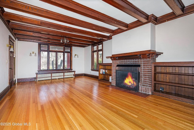 unfurnished living room featuring beam ceiling, hardwood / wood-style floors, radiator, baseboards, and a brick fireplace