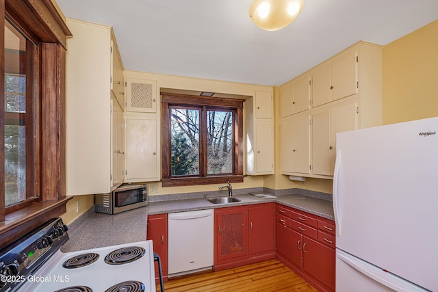 kitchen with white appliances, visible vents, light wood-style flooring, a sink, and dark countertops