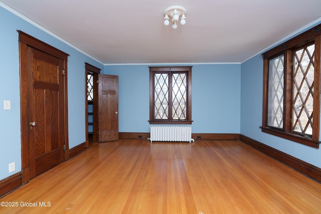 unfurnished room featuring crown molding, light wood-style flooring, radiator, and baseboards