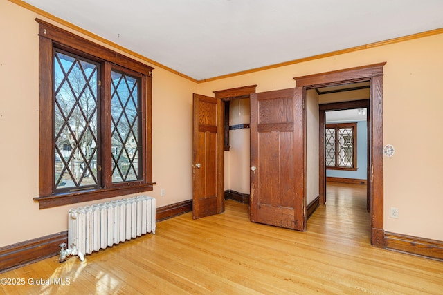 unfurnished bedroom with light wood-style floors, baseboards, radiator, and ornamental molding