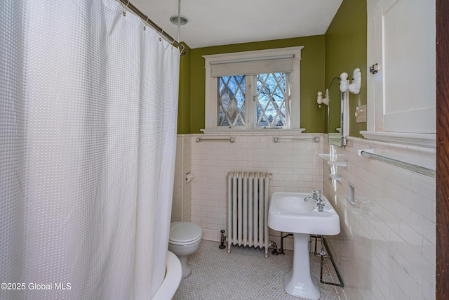 full bath with a shower with curtain, radiator heating unit, tile patterned floors, toilet, and tile walls