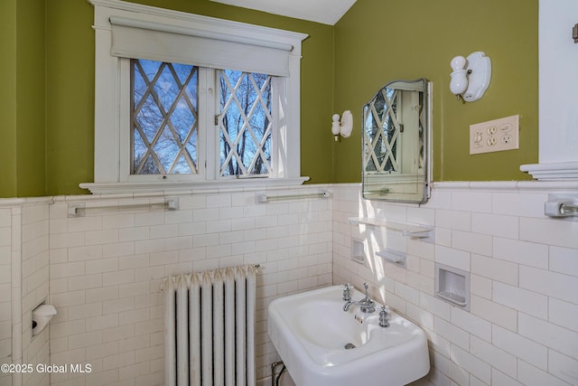 half bathroom featuring wainscoting, radiator, and a sink