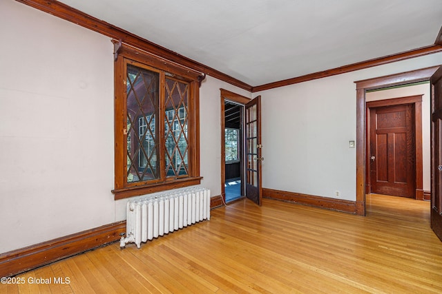 unfurnished room with light wood-style flooring, radiator, crown molding, and baseboards