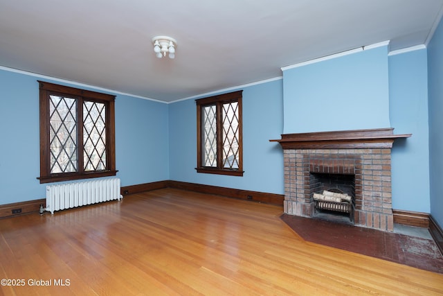 unfurnished living room featuring radiator heating unit, wood finished floors, and ornamental molding