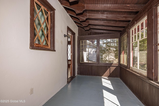 corridor featuring lofted ceiling and wooden walls