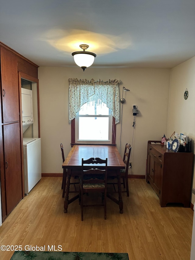 dining room with baseboards, light wood-style flooring, and stacked washing maching and dryer