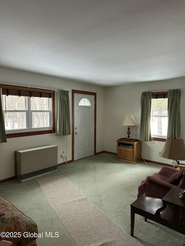 foyer entrance with baseboards, light colored carpet, and heating unit