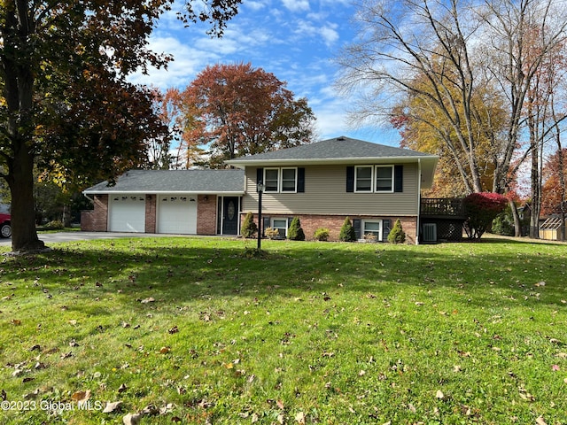 split level home featuring a front lawn, brick siding, driveway, and an attached garage