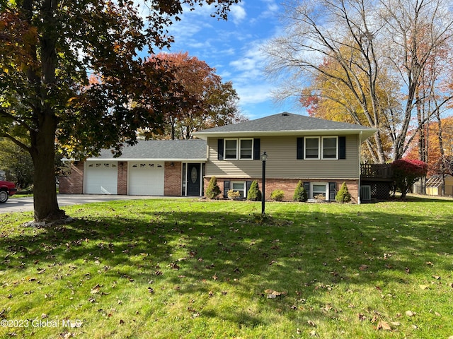 tri-level home featuring an attached garage, a front lawn, concrete driveway, and brick siding