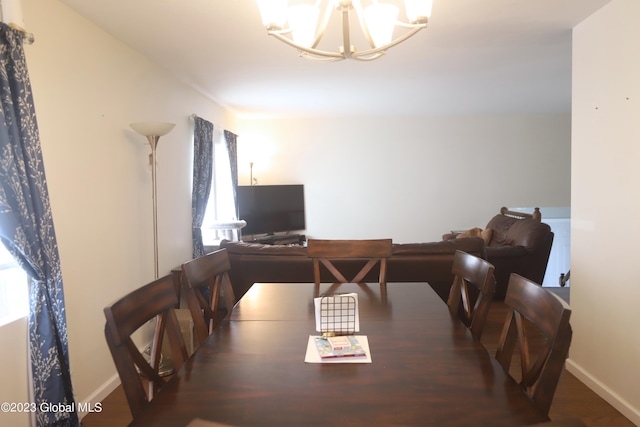 dining space featuring baseboards, wood finished floors, and a notable chandelier