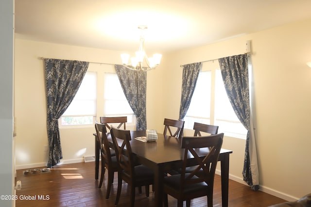 dining space featuring baseboards, wood finished floors, and a notable chandelier