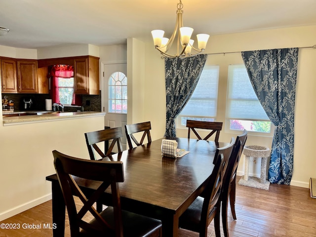 dining area with baseboards, wood finished floors, and an inviting chandelier