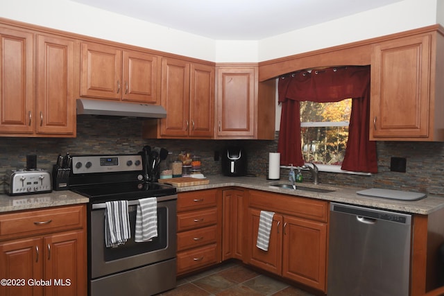 kitchen with tasteful backsplash, brown cabinets, stainless steel appliances, under cabinet range hood, and a sink