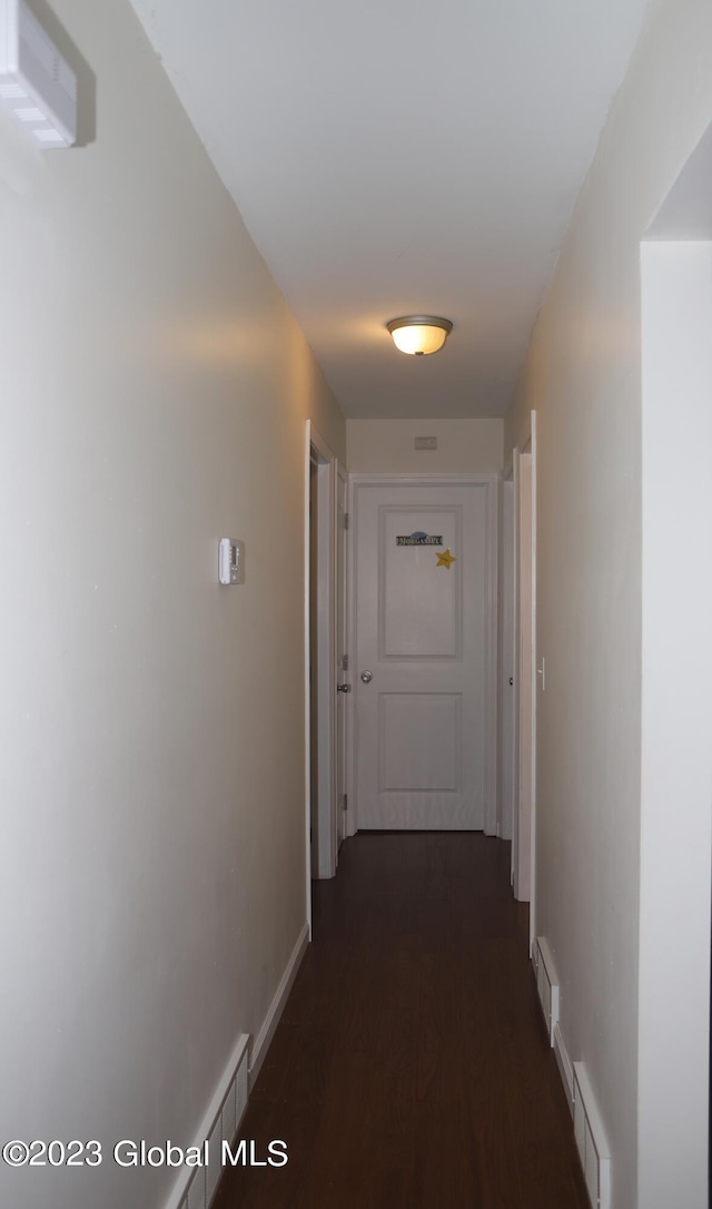 hall featuring dark wood-style floors, baseboards, and visible vents