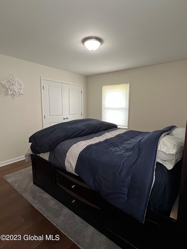 bedroom featuring a closet, dark wood finished floors, and baseboards