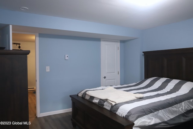 bedroom with a baseboard radiator, baseboards, and dark wood finished floors