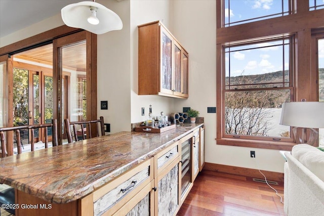 kitchen with a wealth of natural light, light stone counters, and wood finished floors