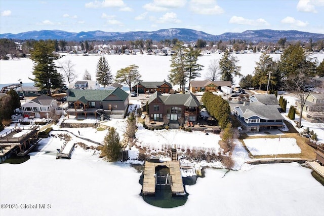 snowy aerial view featuring a mountain view and a residential view