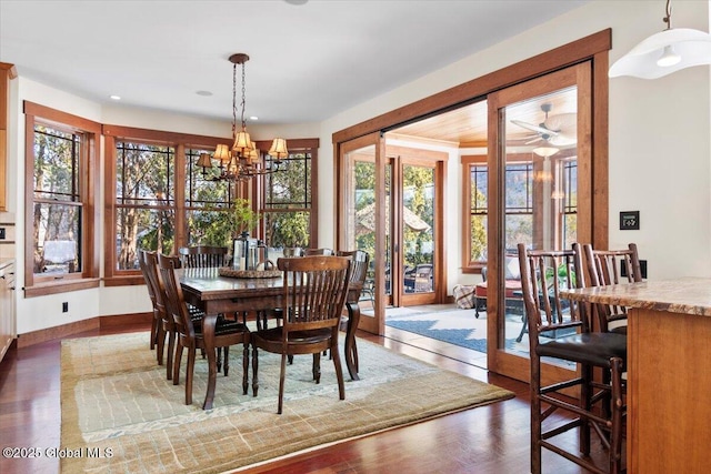 dining space with arched walkways, a notable chandelier, baseboards, and wood finished floors