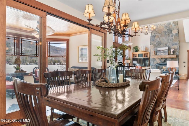 dining space featuring an inviting chandelier, wood finished floors, a fireplace, and crown molding