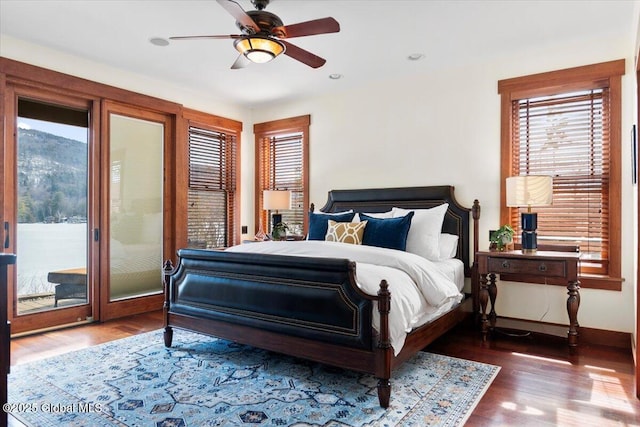 bedroom with access to outside, multiple windows, wood finished floors, and baseboards