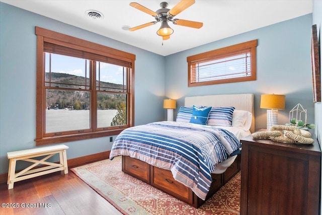 bedroom with visible vents, a ceiling fan, baseboards, and wood finished floors