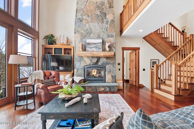 living room featuring a towering ceiling, stairs, wood finished floors, and a fireplace