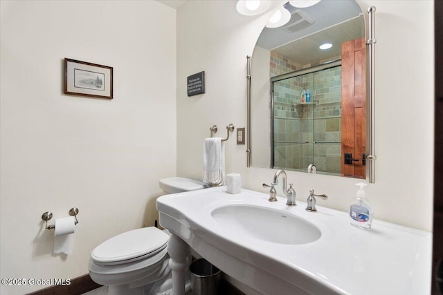 bathroom featuring a sink, toilet, and a shower stall