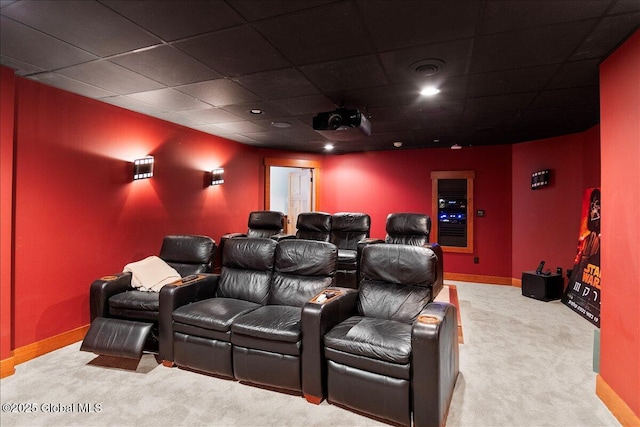 carpeted home theater with a paneled ceiling, baseboards, and visible vents