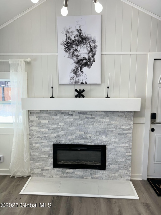 interior details featuring crown molding, wood finished floors, and a stone fireplace