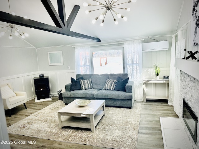 living area featuring a notable chandelier, a decorative wall, wood finished floors, a fireplace with flush hearth, and a wall mounted air conditioner