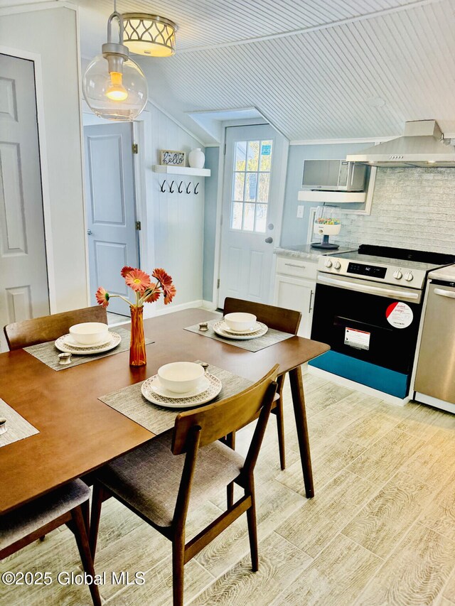 dining space featuring lofted ceiling and light wood-style flooring