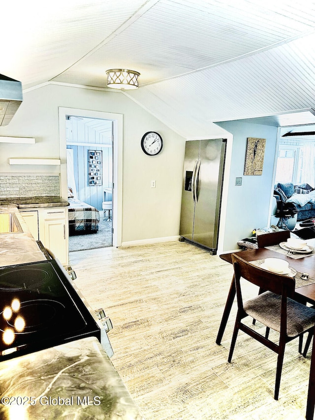 kitchen with electric range oven, stainless steel refrigerator with ice dispenser, lofted ceiling, and white cabinets