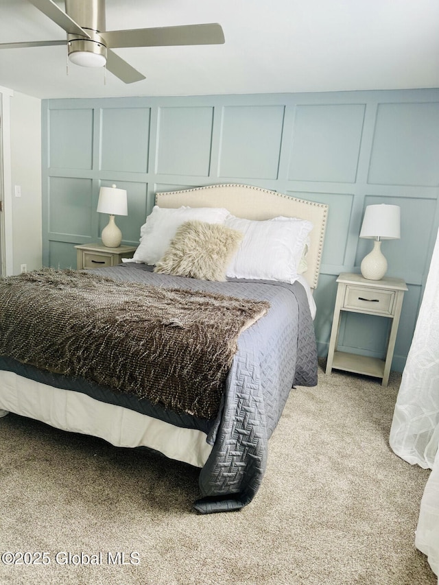 bedroom featuring ceiling fan, light colored carpet, and a decorative wall