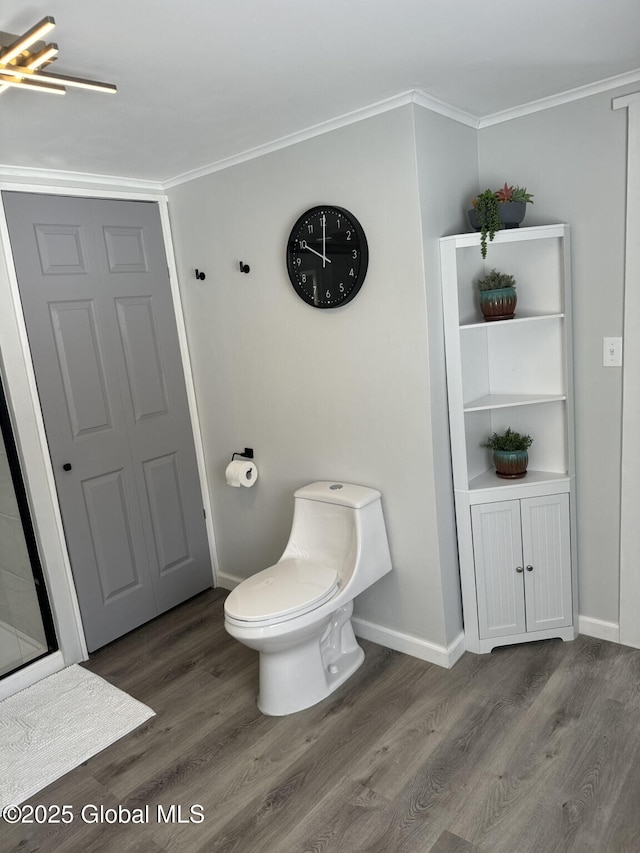 bathroom with baseboards, crown molding, toilet, and wood finished floors