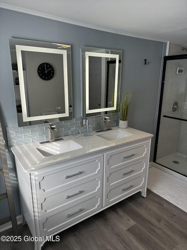 bathroom featuring crown molding, tasteful backsplash, a sink, and wood finished floors