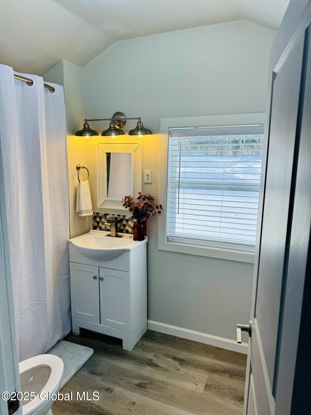 full bathroom featuring vaulted ceiling, vanity, baseboards, and wood finished floors