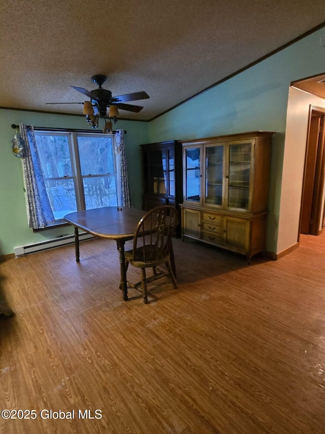 unfurnished dining area with crown molding, a textured ceiling, a baseboard heating unit, and wood finished floors