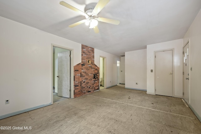 unfurnished living room with a ceiling fan, baseboards, and brick wall