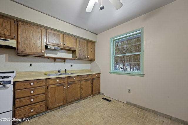 kitchen featuring white gas range oven, visible vents, light countertops, under cabinet range hood, and a sink